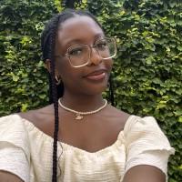 Eniola Olaleye in glasses wearing a white top, looking directly at the camera with a neutral expression.