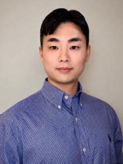 Professional headshot of a young man with short black hair wearing a blue button-down shirt, facing the camera with a calm, neutral expression.