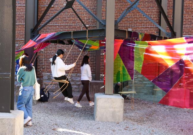 Knitted pillows and swinging elements invite viewers to pause, reflect and engage with the installation’s immersive atmosphere. Photo by Haley Simpkins.